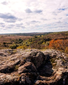 fantastic autumn in a mountain canyon, huge rocks. big gray granite boulders on top of a mountain, stone valley. yellow and red trees grow among the rocks. Aktovsky Canyon, Ukraine with rocks.