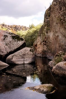 Beautiful blue lake with boulder figures. in a mountain valley there is a lake with stones. fantastic granite gray boulders protrude from the water, close-up Aktovsky canyon, Ukraine. vertical photo