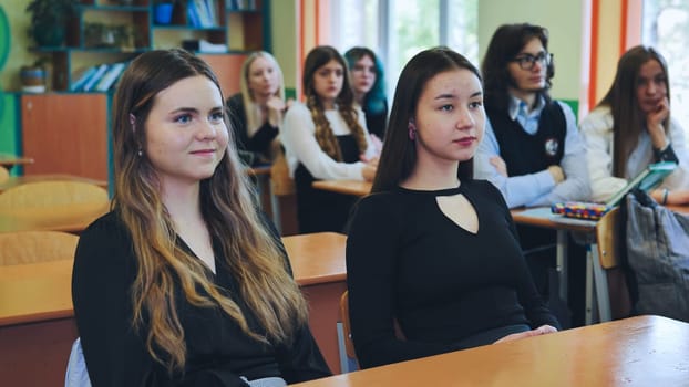 Group of teenage high school students listening to their teacher during a lesson in the classroom