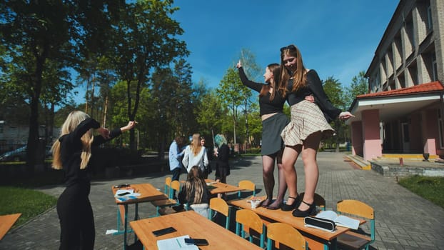 Students happily dancing on school desks in the schoolyard during break time, cherishing their youth and camaraderie