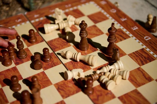 A wooden chessboard displays scattered chess pieces, showcasing the aftermath of an intense game.
