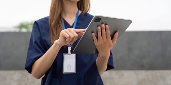 A nurse in scrubs focuses on her tablet, managing patient information and documentation, highlighting the integration of technology in healthcare.