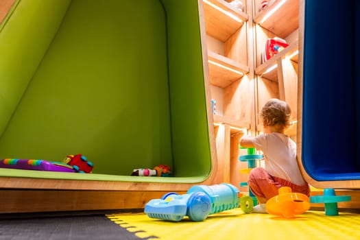 Little child enjoying creative playtime with a toy vacuum cleaner in a bright and interactive playroom