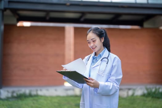 A focused doctor in a white coat smiles while reviewing patient documents on a clipboard, emphasizing dedication to quality care and professionalism in healthcare.