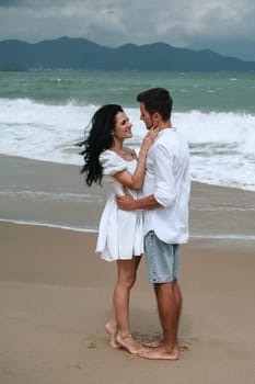 Happy young beautiful couple in love hugging on the beach by the sea in summer on vacation