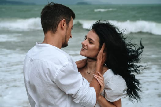 young beautiful couple in love hugging on the beach by the sea in summer close up