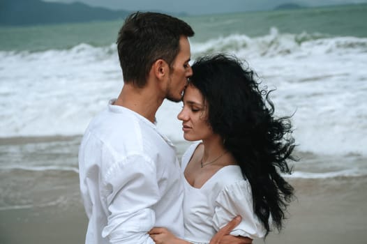 young beautiful couple in love kissing on the beach by the sea in summer on vacation close-up