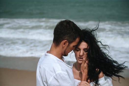 beautiful couple in love hugging on the beach by the sea in summer on vacation