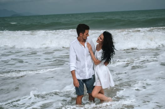 Happy young couple in love on the beach by the sea in summer