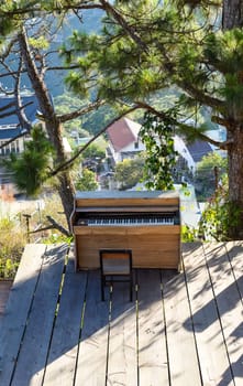 Piano under a pine tree in under sun beams in the city of Da Lat in mountains