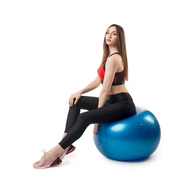 Slim fitness model in sportswear exercising with fitball isolated full-length view