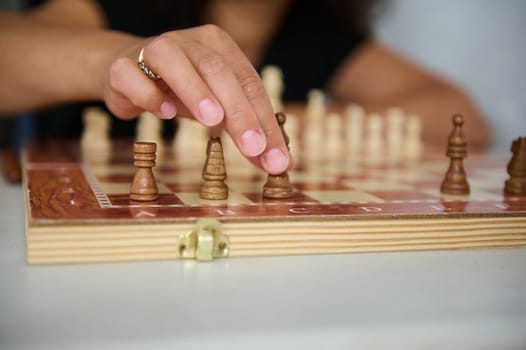 A close-up photograph of a chess player moving a chess piece on the board.