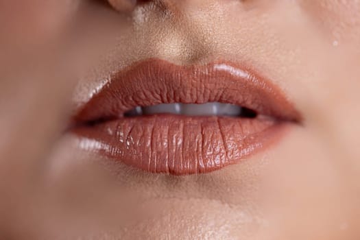 A stunning closeup image highlighting glossy, beautiful lips that showcase a popular, trendy nude lip color and shine