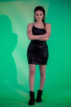 A chic and fashionable woman confidently poses in a stunning black dress against a striking and vibrant green backdrop