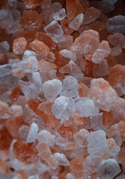 Close-up view of Pink Himalayan Salt on Bright colors textured surface. Crystals and crushed blocks of natural pink salt in the background, Chipped Himalayan salt stone, use it as your Space for text, Design, Wallpaper and Poster, Selective focus.