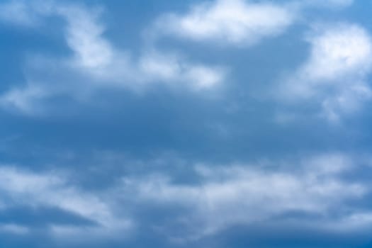 Thick clouds blanket the sky, creating a tranquil yet dynamic ambiance as afternoon light gently filters through. The varying shades of blue evoke a calm and serene atmosphere.