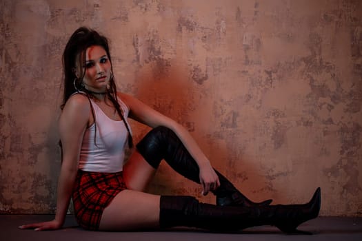 A confident young woman poses stylishly in contemporary fashion against a textured artistic background