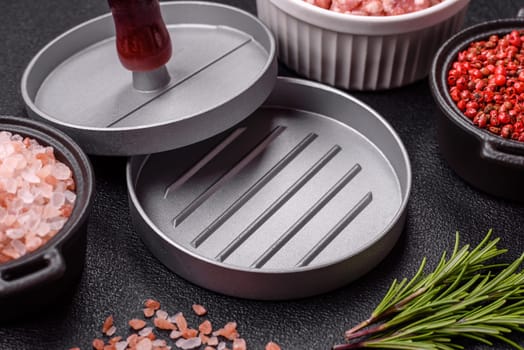Metal press for making minced meat cutlets for burgers on a dark concrete background