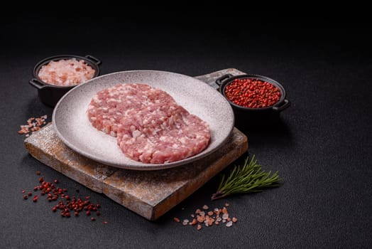Fresh raw ground beef or pork burger patty with salt and spices on textured concrete background