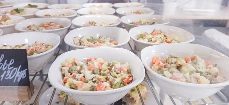 Colourful bowls filled with fresh vegetable salads showcase a variety of ingredients at a bustling local market. Visitors explore the vibrant selection in the afternoon light.