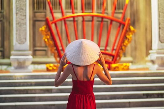 woman in a traditional Vietnamese Non La hat in temple on a Buddhist pagoda in Vietnam. The concept of travel in Asia