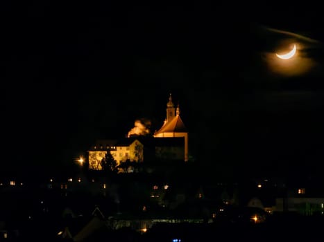 Franziskanerkloster Frauenberg mit Stiftskirche in Fulda, Deutschland, bei Nacht im Mondlicht und hellen Lichtern, in der Ferne. High quality photo
