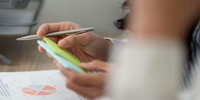 A business professional focuses on analyzing notes and data charts, using a pen to emphasize key information during discussions.