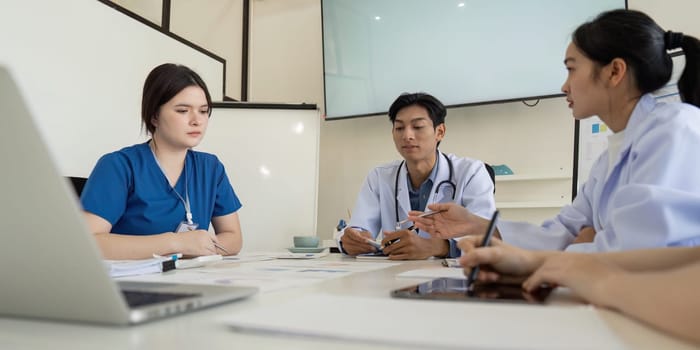 A diverse team of healthcare professionals participating in a focused meeting, discussing strategies and analyzing data to improve patient care outcomes.