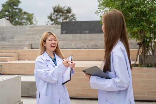 Two diverse female doctors joyfully discussing patient care outside a medical facility, emphasizing collaboration and a positive atmosphere in healthcare.