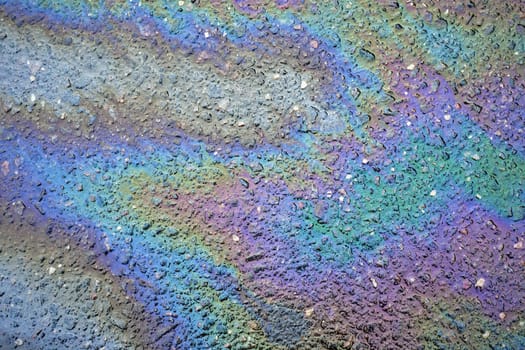 Close-up of multicolored fuel spills, revealing a rich backdrop of various shades on the roadway