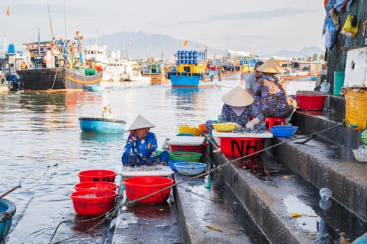 Vietnamese women sit on the steps of the seaport and sell fresh fish. Vietnam, Nha Trang - September 8, 2024