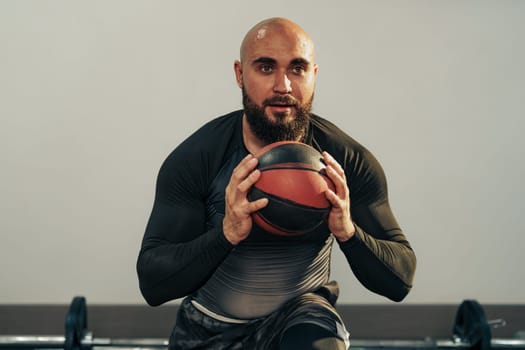 A focused individual performs an exercise with a medicine ball, displaying determination and strength. The gym atmosphere is energetic, filled with workout equipment.