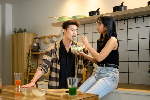 Young couple enjoying cooking and tasting together in the Kitchen.