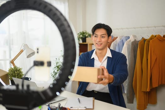 Young entrepreneur presenting a package to the camera during live online selling session.
