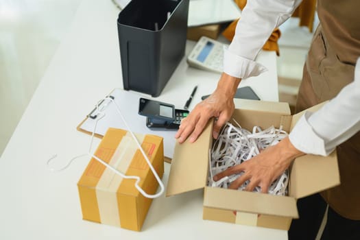 Close up of an entrepreneur preparing package with shredded paper for shipment.