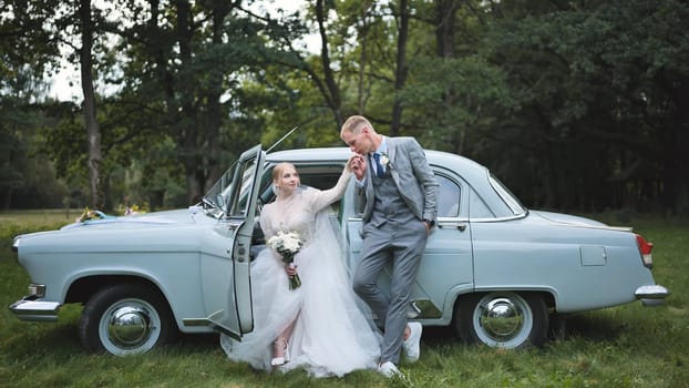 Romantic couple embracing near classic convertible, wedding attire gleaming against scenic landscape backdrop
