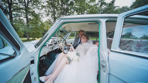 Bride and groom sitting together in a vintage car, savoring a romantic moment and celebrating their love on a beautiful wedding day