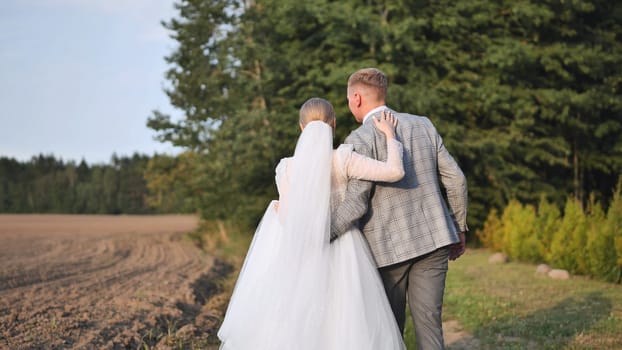 Newlywed couple walking away, seen from behind, enjoying a peaceful moment in nature during their wedding day