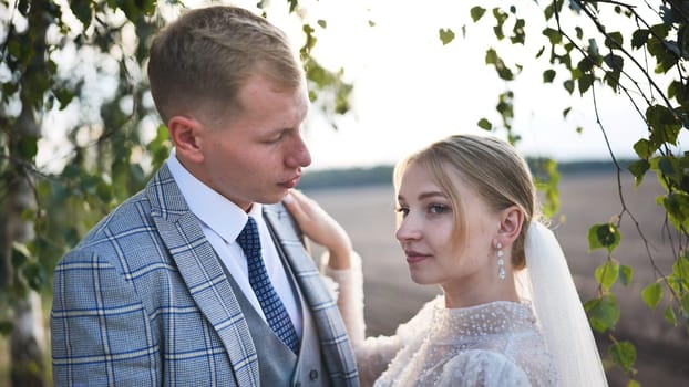 Newlywed couple embracing beneath birch branches, representing romantic connection, commitment, and new life chapter