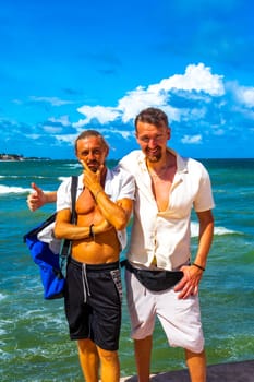 Male tourists men best friends guys are posing for a photo selfie model and having fun swimming on the mexican Caribbean beach in Playa del Carmen Quintana Roo Mexico.