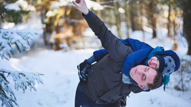 Father and son enjoying a winter day playing together in the snowy forest, strengthening their bond and creating happy memories