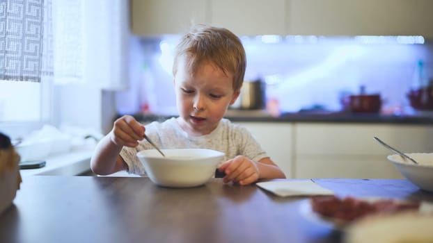 Blond child warming hands around steaming soup bowl, savoring comforting winter lunch indoors