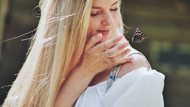 Blonde woman gently observing a colorful butterfly landing on her hand, enjoying a moment of connection with nature
