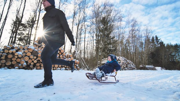 Father pulling his son on a sled through a snowy forest, sharing laughter and joy on a sunny winter day filled with adventure