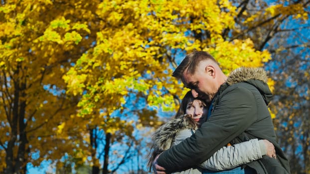 Romantic couple embracing beneath golden autumn trees, enjoying a peaceful moment together in a serene park filled with vibrant fall colors