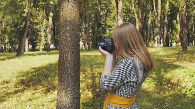 Female photographer capturing stunning images in a park, enjoying the beautiful sunlight and vibrant nature on a perfect summer day