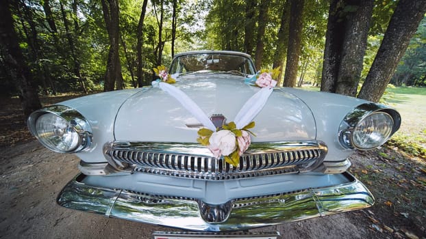 Vintage white volga m21 adorned with floral decorations, standing on forest road during wedding celebration, romantic automotive scene
