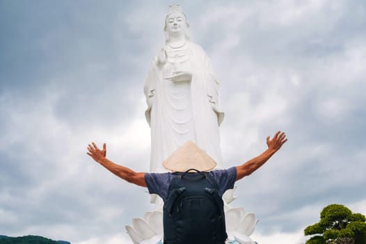 back of a male tourist traveler at Lady Buddha statue at the Linh Ung Pagoda in Da Nang in Vietnam. Concept of travel and tourism in Asia