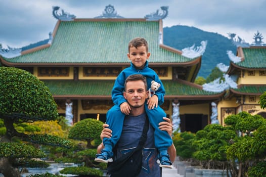 Happy family of tourists dad and son at Buddhist temple at Linh Ung Pagoda in Da Nang in Vietnam. Travel and tourism in Asia