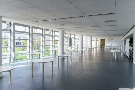 This modern Indoor space has natural light from large windows, creating an inviting atmosphere. With minimalist tables, its ideal for hosting events and ensuring a great experience